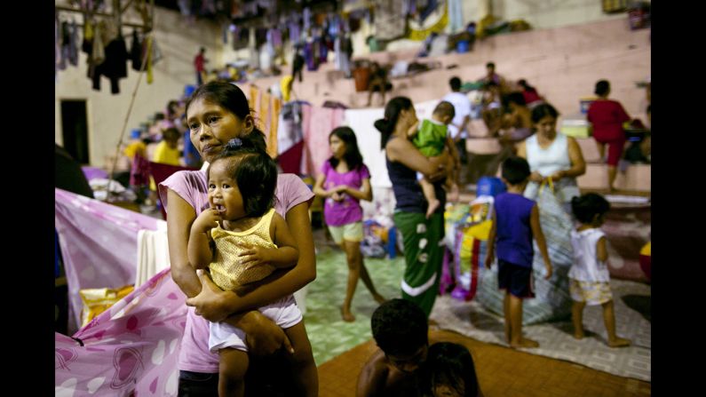 Displaced flood victims pack a crowded evacuation center in a flooded neighborhood.