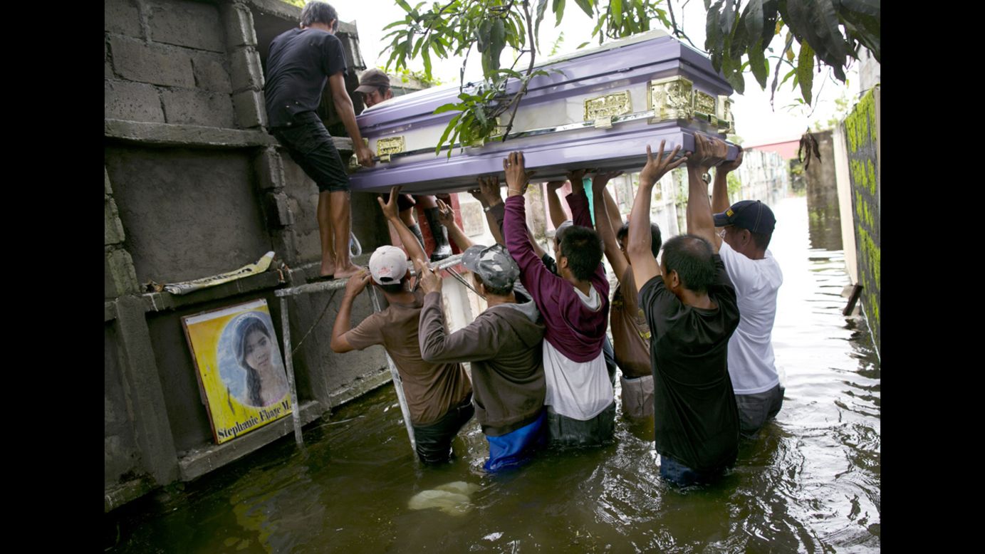 Locals lift the casket of Nelida Gregorio, 89, who died of a heart attack, into a grave site in a flooded cemetery. 