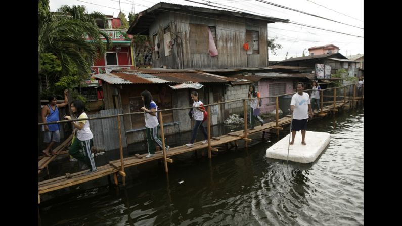 Filipino students walk on a footbridge on a road that remains flooded a week after heavy monsoon rains in Taguig City, south of Manila, Philippines, August 16, 2012. A tropical storm hit the Northern Luzon, bringing days of wet weather to a region still recovering from massive flooding. According to the Office of Civil Defense, the floods have left at least 96 people dead and affected up to 2.68 million people.