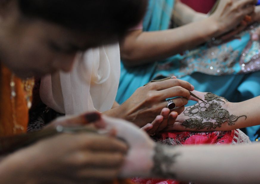 Beauticians apply traditional henna designs to the hands of customers ahead of the Muslim festivities of Eid al-Fitr in Karachi.
