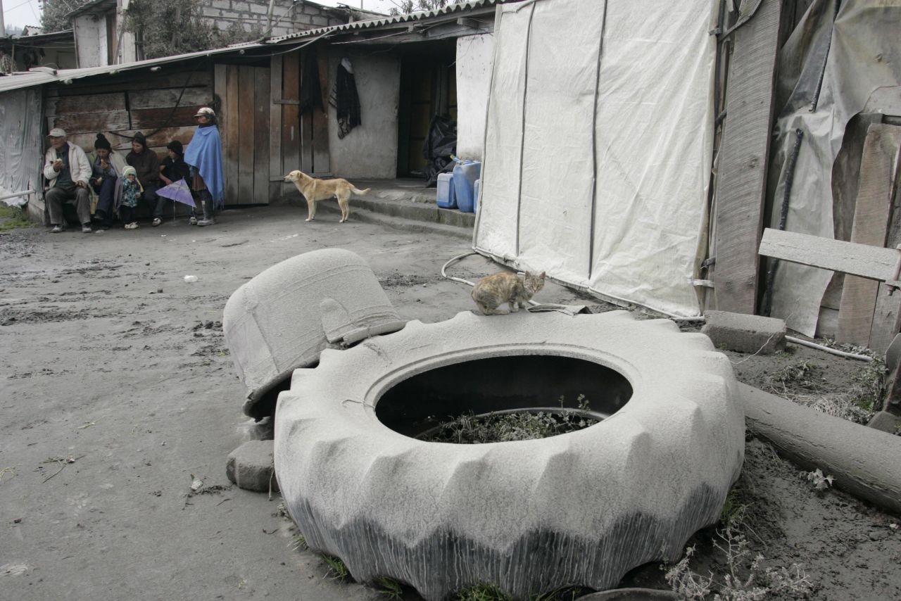Residents take cover Sunday near Banos as the volcano spews large clouds of gas and ash.