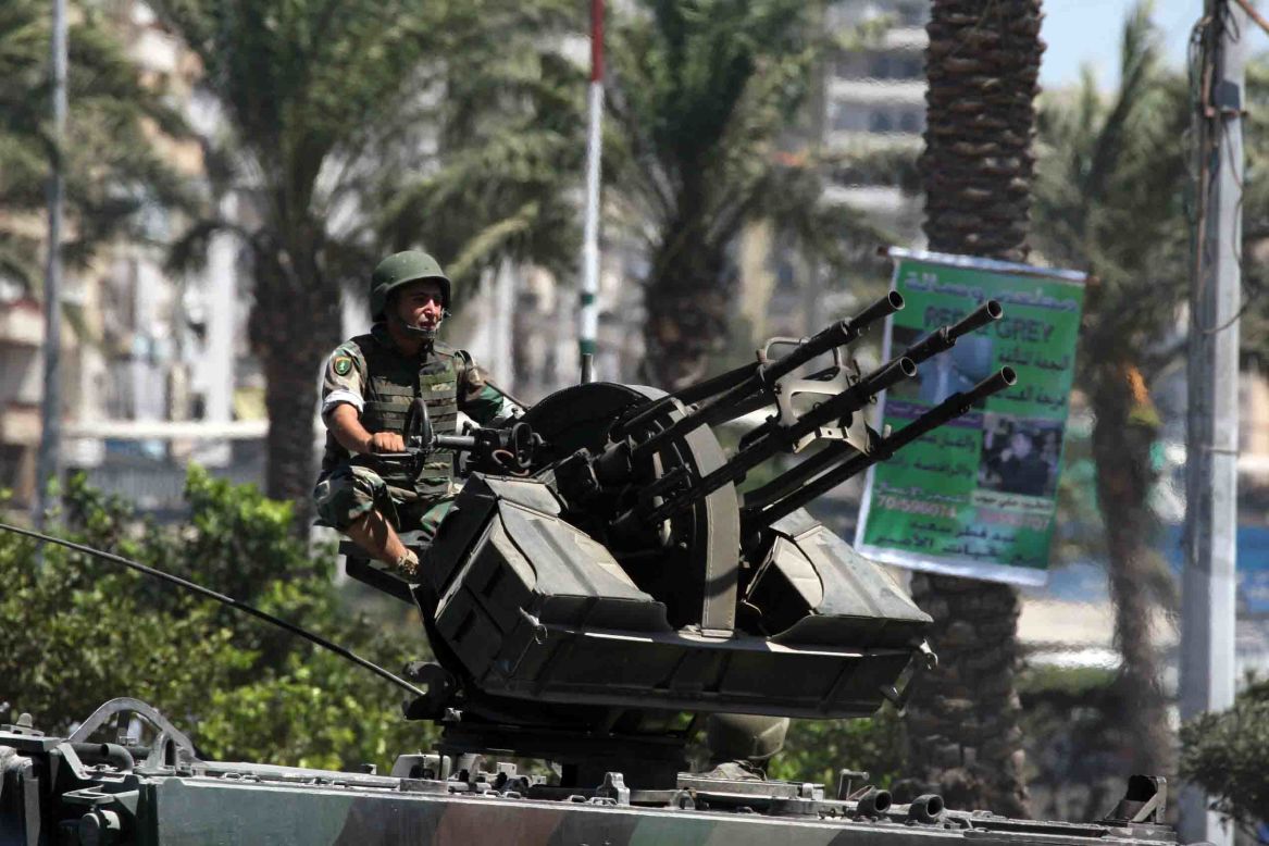 A Lebanese soldier mans an anti-aircraft heavy machine gun mounted on an armored personal carrier Wednesday in Tripoli. The Syrian civil war has aggravated decades-old quarrels in two of the city's neighborhoods.