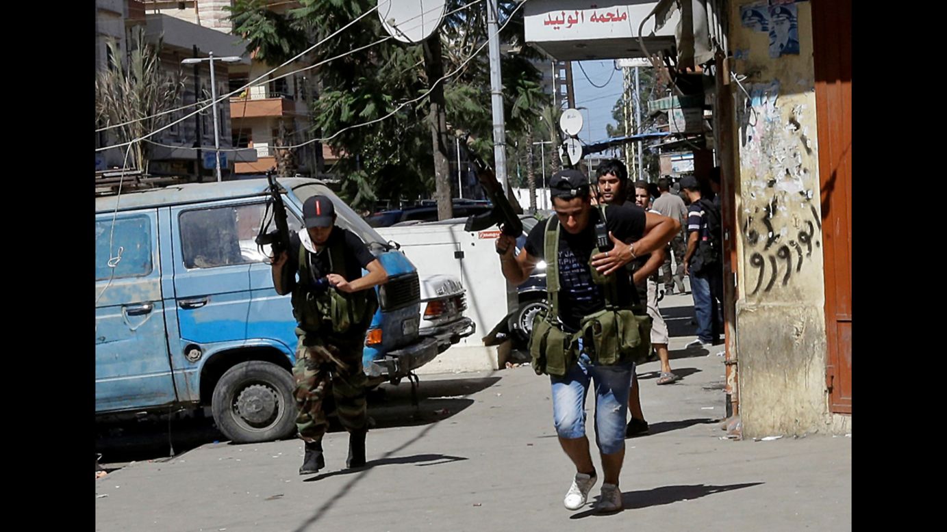 Supporters of the Syrian uprising run down a street in Tripoli's Bab al Tabaneh neighborhood Wednesday. Sniper fire broke out in two neighborhoods of the Lebanese seaport: one dominated by Alawite Muslims, the other by Sunni Muslims.