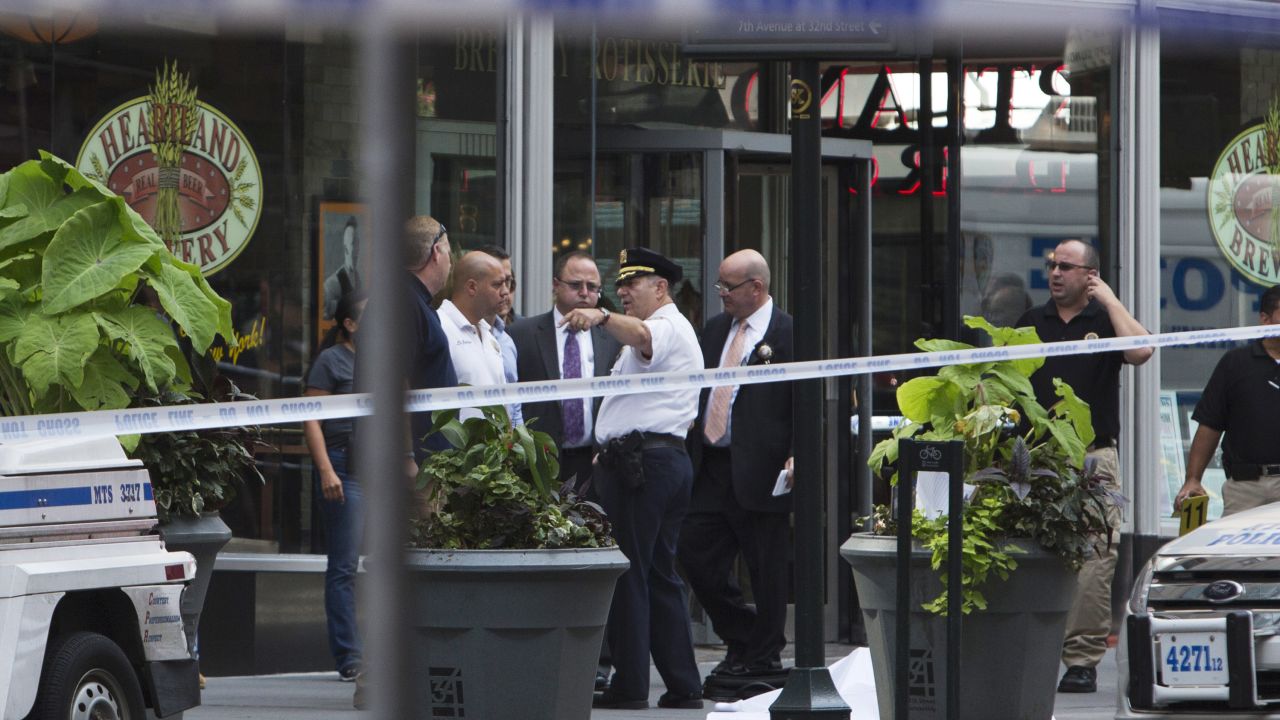 Law enforcement stands near the covered body of the suspected shooter near the Empire State Building on August 24.