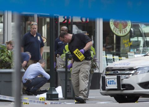 Law enforcement officers stand near the covered body of the suspected shooter on Fifth Avenue. The man opened fire outside the building's Fifth Avenue entrance, triggering a gunbattle with police, authorities said.