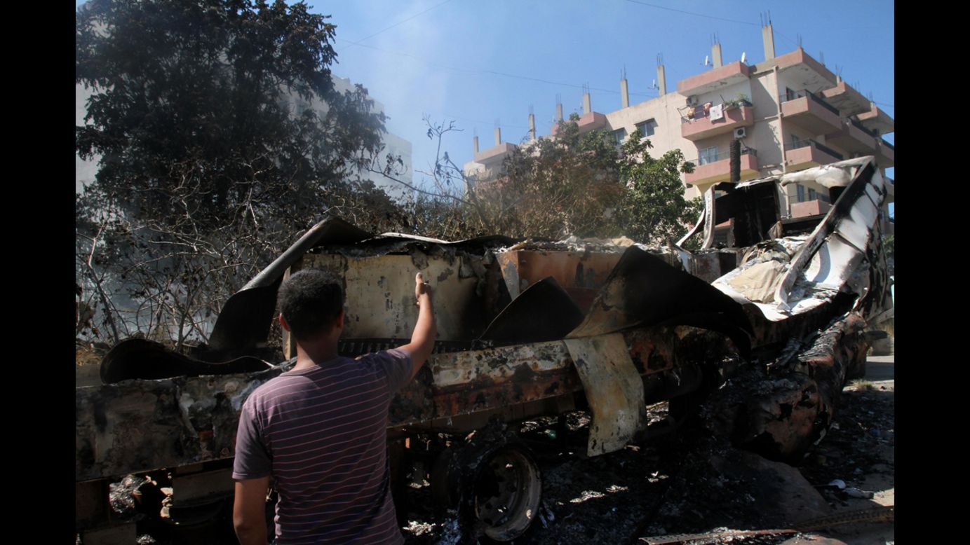 A Lebanese man points at burned vehicles in the Bab al-Tabbaneh neighborhood in Tripoli, Lebanon, on Thursday, August 23. Fresh fighting erupted in Bab al-Tabbaneh, leaving one dead and two wounded, a security source said, despite a truce to halt days of violence between pro- and anti-Damascus gunmen. 