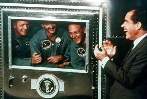 President Richard Nixon applauds the Apollo 11 astronauts, who were confined in a quarantine trailer after their flight, on July 25, 1969.