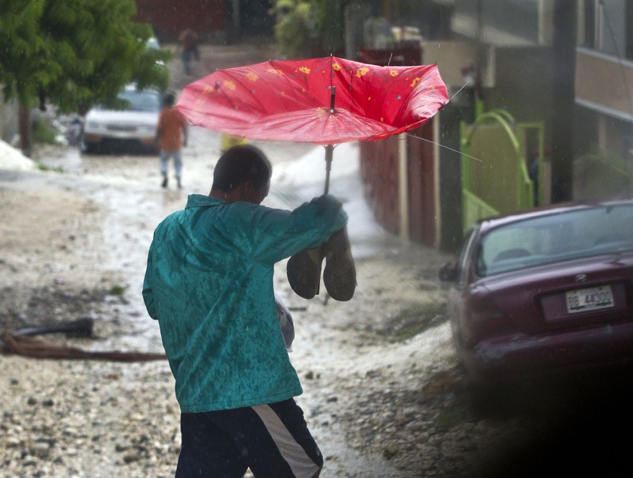 A man tries to stay dry in Port au Prince, Haiti, after Tropical Storm Isaac hit in  August, 2012.
