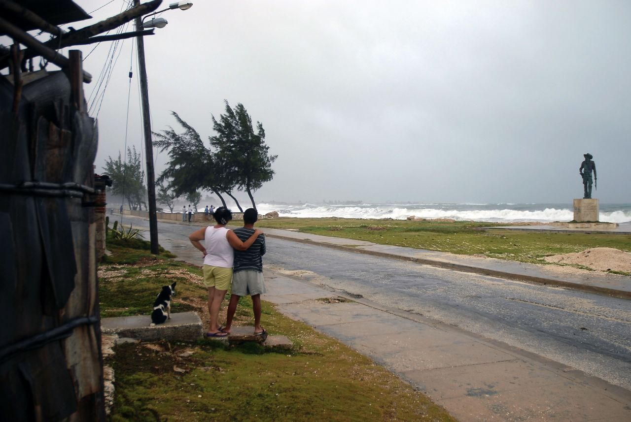 A couple watch as waves and strong winds from Tropical Storm Isaac, which crossed Cuba on Sunday, batter the shore in Gibara, Cuba, on Saturday.