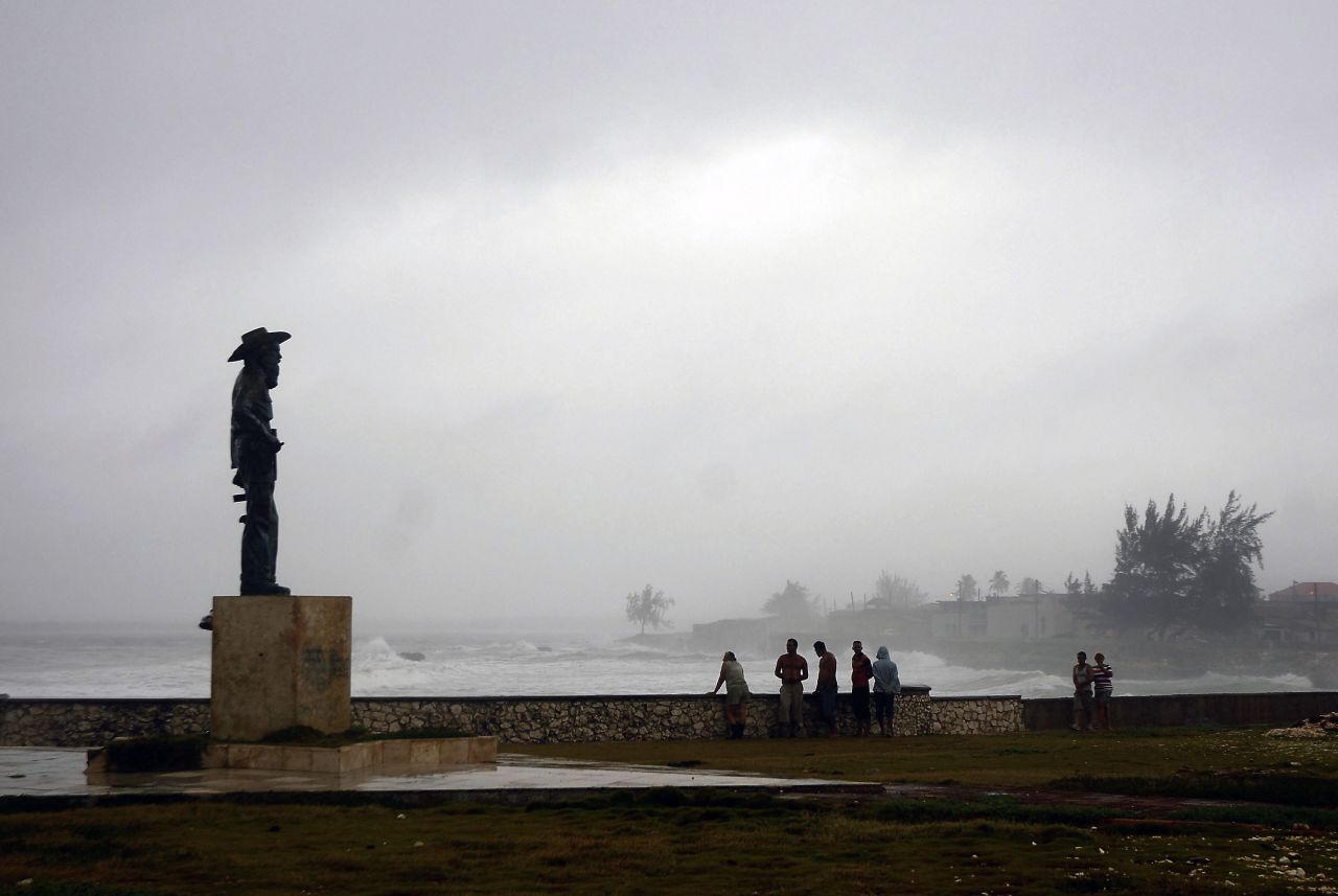 People watch from the shore as waves pound the coast in Gibara.
