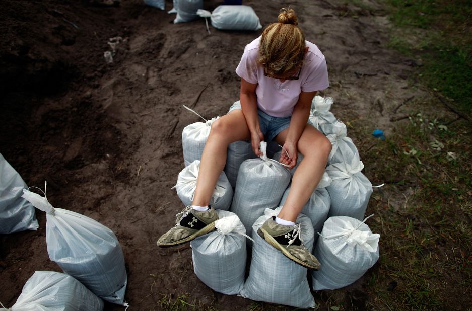 A woman sits atop sandbags filled by Tampa area residents in preparation for the storm.