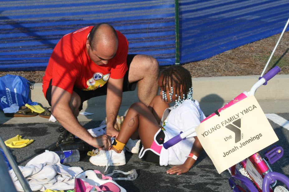 Jonah Jennings gets help from a race volunteer as she puts her sneakers on after the swim. 