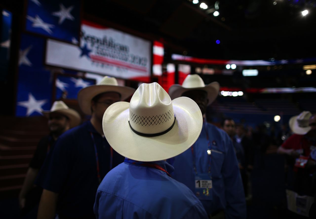Men wearing cowboy hats stand on the arena floor before the start of the abbreviated first day.