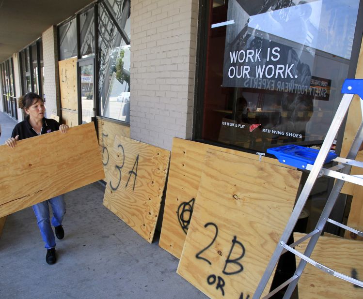 The manager of a shoe store in Harvey, Louisiana, places plywood over the windows in preparation of Hurricane Isaac.