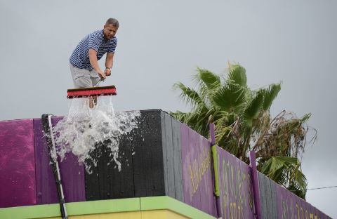 Oliver Marti sweeps water from heavy rains generated by Tropical Storm Isaac off the roof of his flower shop on  Monday in Tampa, Florida. 