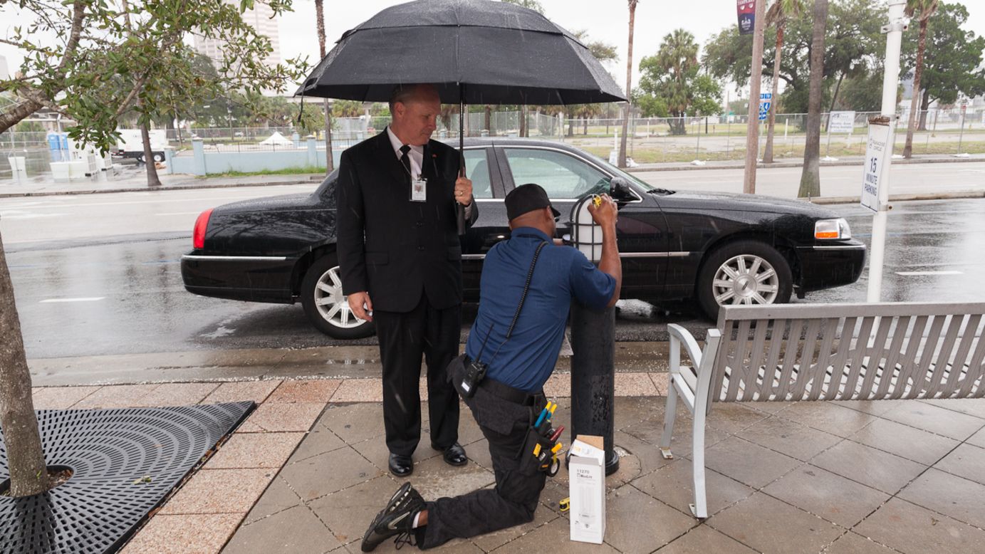 An electrician at the Tampa Bay Times Forum fixes a light as a limo driver awaits Republican delegates.