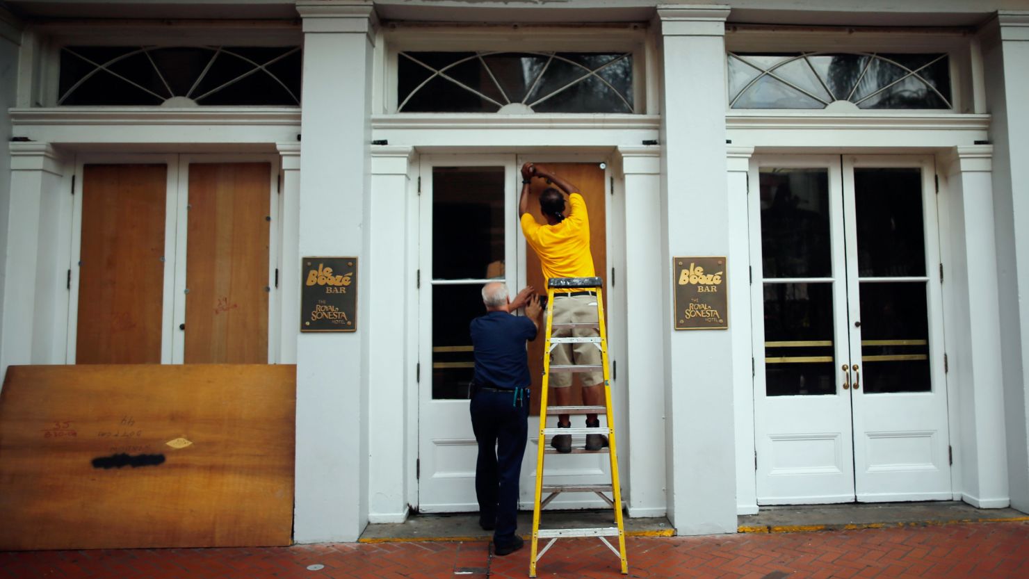 Workers place plywood on the windows of the Royal Sonesta Hotel in New Orleans on Monday to prepare for Isaac.