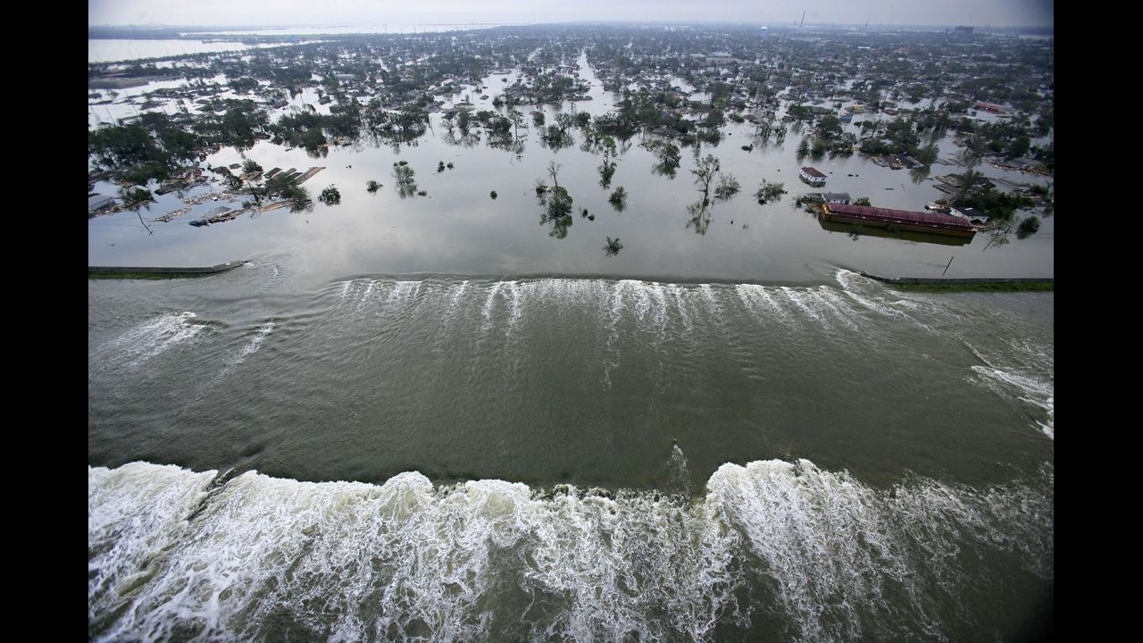 Water spills over a levee along the Inner Harbor Navigational Canal in the aftermath of Hurricane Katrina on August 30, 2005, in New Orleans. Katrina struck the Gulf Coast on August 29, 2005. After levees and flood walls protecting New Orleans failed, much of the city was underwater.