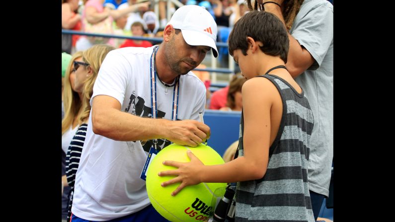 Golfer Sergio Garcia of Spain signs an autograph for a fan as James Blake of the United States and Lukas Lacko of Slovakia compete.