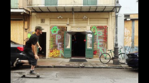 A man skateboards past a bar with boarded windows in the French Quarter in New Orleans. 