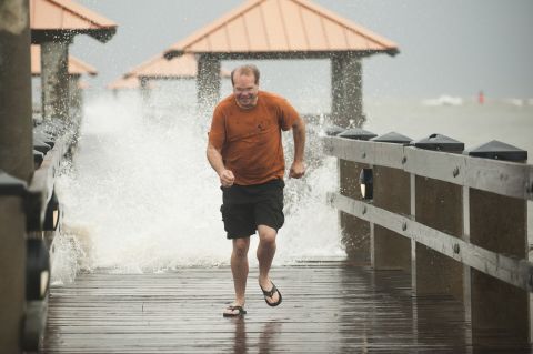 Scott Burley runs from crashing surf on the Ken Combs Pier in Gulfport, Mississippi.