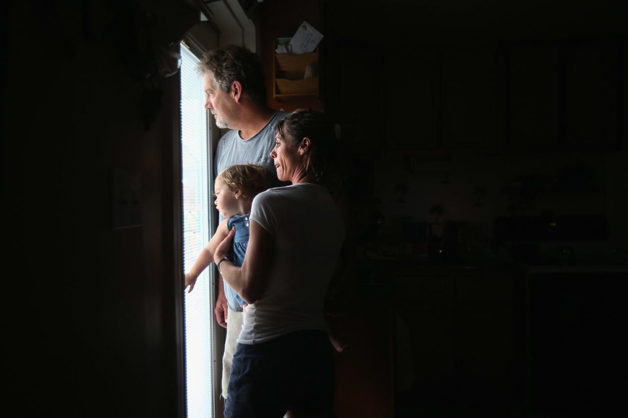 Bridgette Mooney, her husband Kevin, and their 15-month-old daughter Skyler watch from their home as Hurricane Isaac lashes their property with rain in Kiln, Mississippi. 