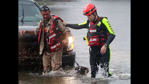John Stone of Bay St. Louis, Mississippi, and his dog are led out of the water by a member of the Swift Water Rescue Team after being rescued from his flooded house.