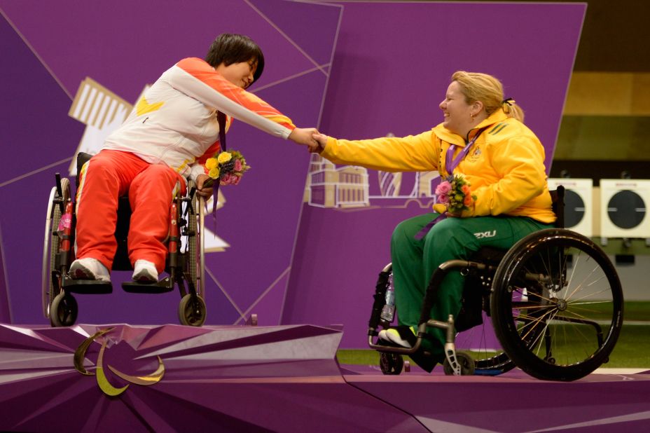 Cuiping Zhang, left, of China and Natalie Smith, right, of Australia shake hands on the podium after the women's R2 10-meter air rifle standing SH1 final.