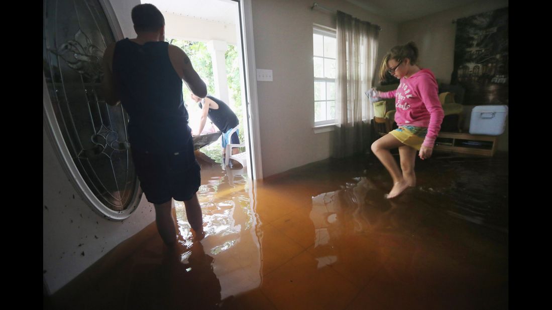 Brittany Trumbaturi, right, prepares to leave her flooded home with family member Joshua Barbot, center, who came to rescue family members in a boat. Officials warned of continued threats from storm surges and flooding as Isaac moved inland.