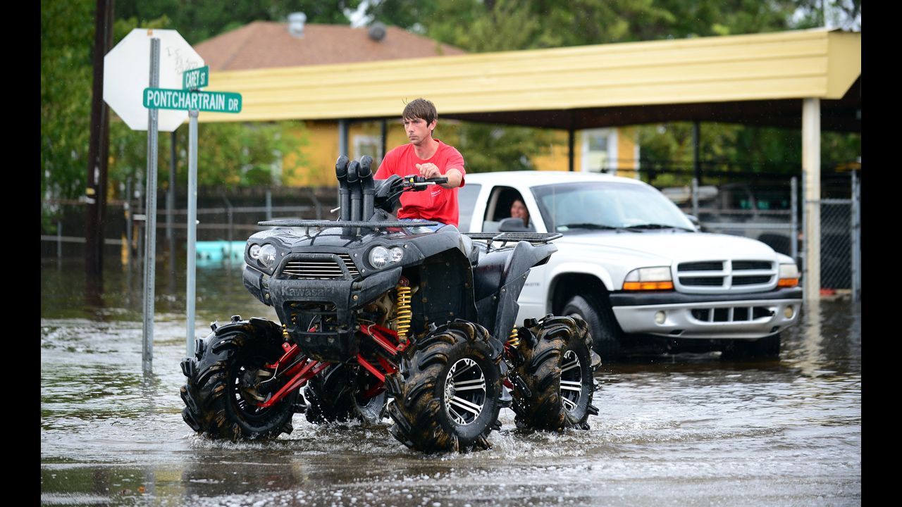 A man drives an off-road vehicle through flooded streets in Slidell.