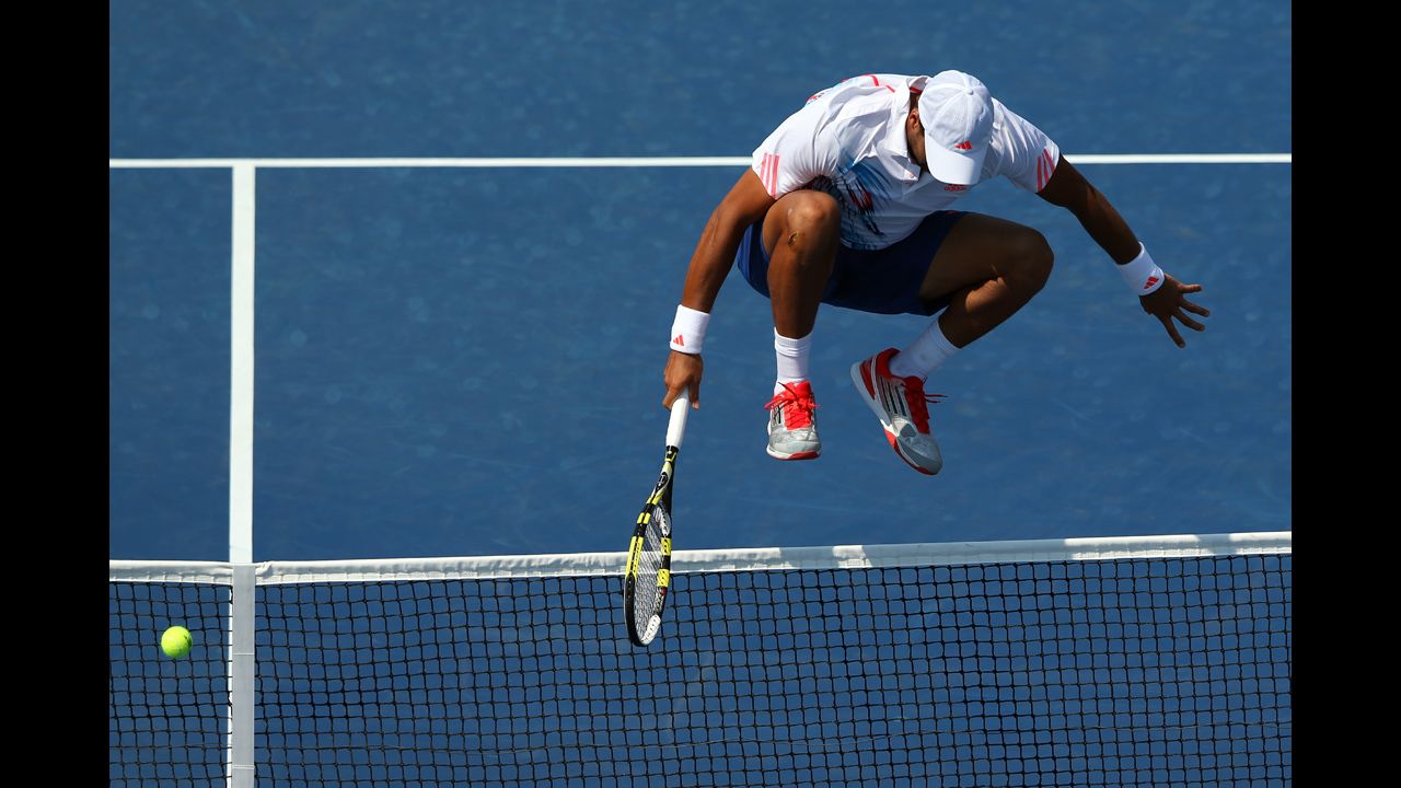 Jo-Wilfried Tsonga of France jumps over the net while trying to return a shot against Martin Klizan of Slovakia.