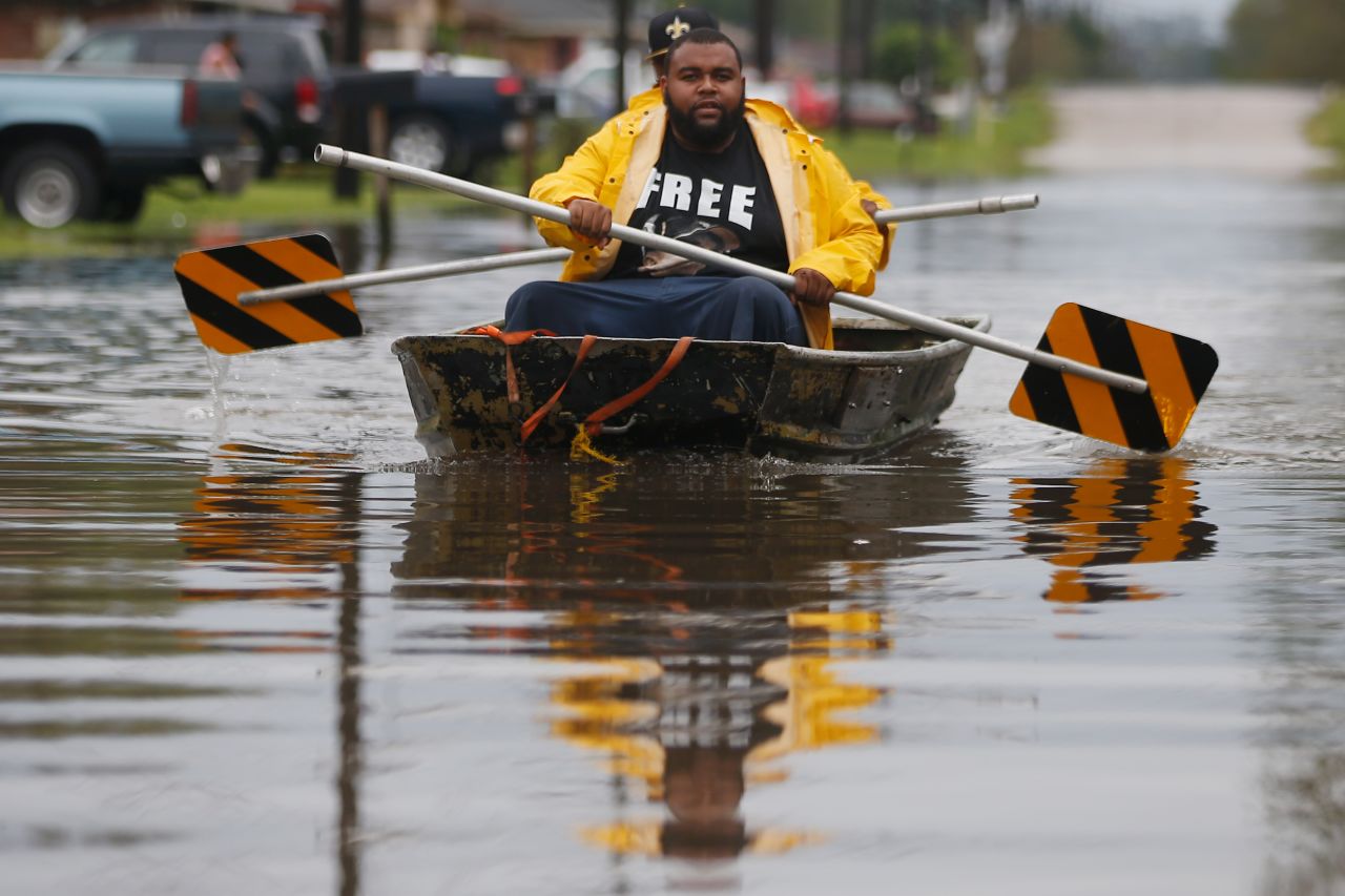 Two men paddle a boat with street signs in flood waters from Hurricane Isaac in Reserve, Louisiana. 