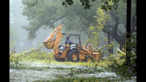A worker in the driving rain tries to clear fallen limbs in the riverbound lanes of Espanade Avenue near McDonogh High School in New Orleans.
