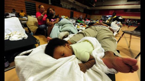 A child and an adult share a folding bed as storm-weary residents take refuge at a high school gymnasium in Belle Chasse, in low-lying Plaquemines Parish, outside of New Orleans.