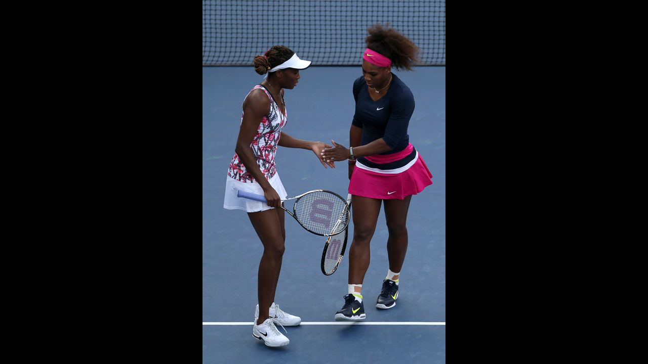 Venus Williams, left, and Serena Williams tap hands during their women's doubles first-round match.