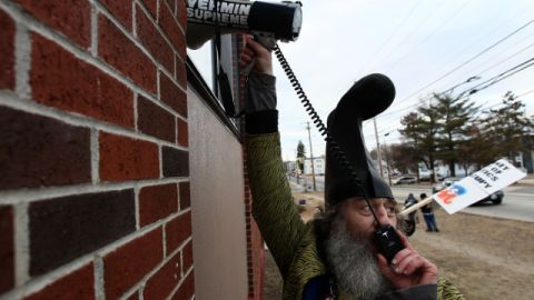 Vermin Supreme places a megaphone against a restaurant where Newt Gingrich is.