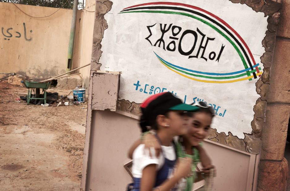 Libyan girls walk past a recently opened Amazigh culture center in Jadu, eastern Libya. The script on the wall is Tifinagh, the Berber alphabet.