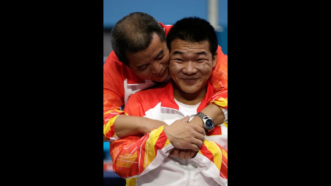 Chinese Qi Feng is congratulated by his coach Weipo Li for his gold during the medal ceremony of the Men's -52 kg powerlifting.