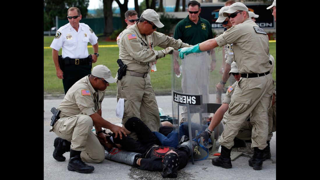 Law enforcement officials work to free protesters with Earth First, who had connected themselves to each other in front of the Big Bend TECO Power Station in Apollo Beach, Florida. Substantially fewer protesters took to the downtown Tampa streets Thursday.