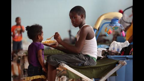 Darrell Hill, 11, feeds his sister Floy Dillon, 2, at a flood shelter set up in a high school gym.