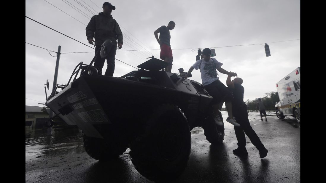 People get off a Slidell Police Department SWAT vehicle after being rescued from flooding from Isaac's storm surge on the north shore of Lake Pontchartrain.