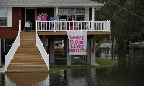 Residents look out from their residence surrounded by water as the motorcade of  Romney passes during a tour of damage from Isaac in Lafitte.