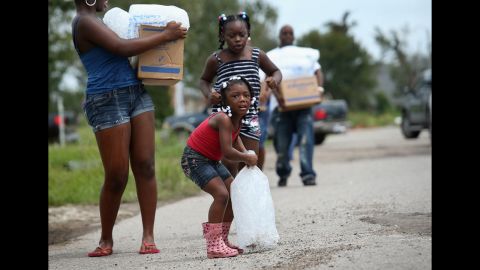  A family carries bags of ice and boxes of food from an aid distribution center for victims of Isaac in New Orleans. The center was one of three in the city operated by the military, offering handouts to residents, many of whom still have no electricity due to the storm.  