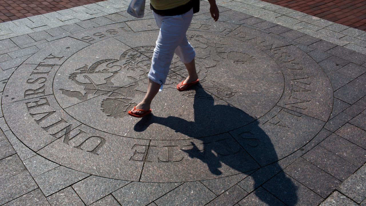 A student traverses the seal of Pennsylvania State University at the center of its University Park campus.