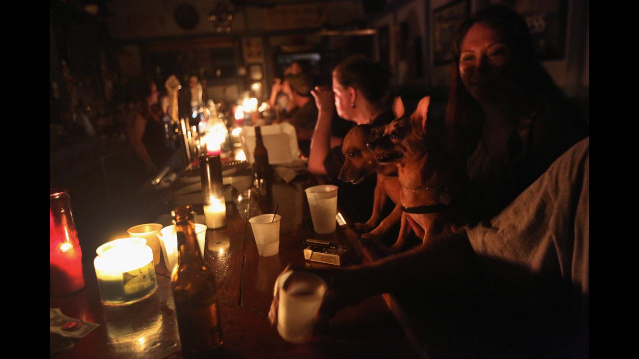  Local residents drink by candlelight at JJ's bar during the continued blackout.