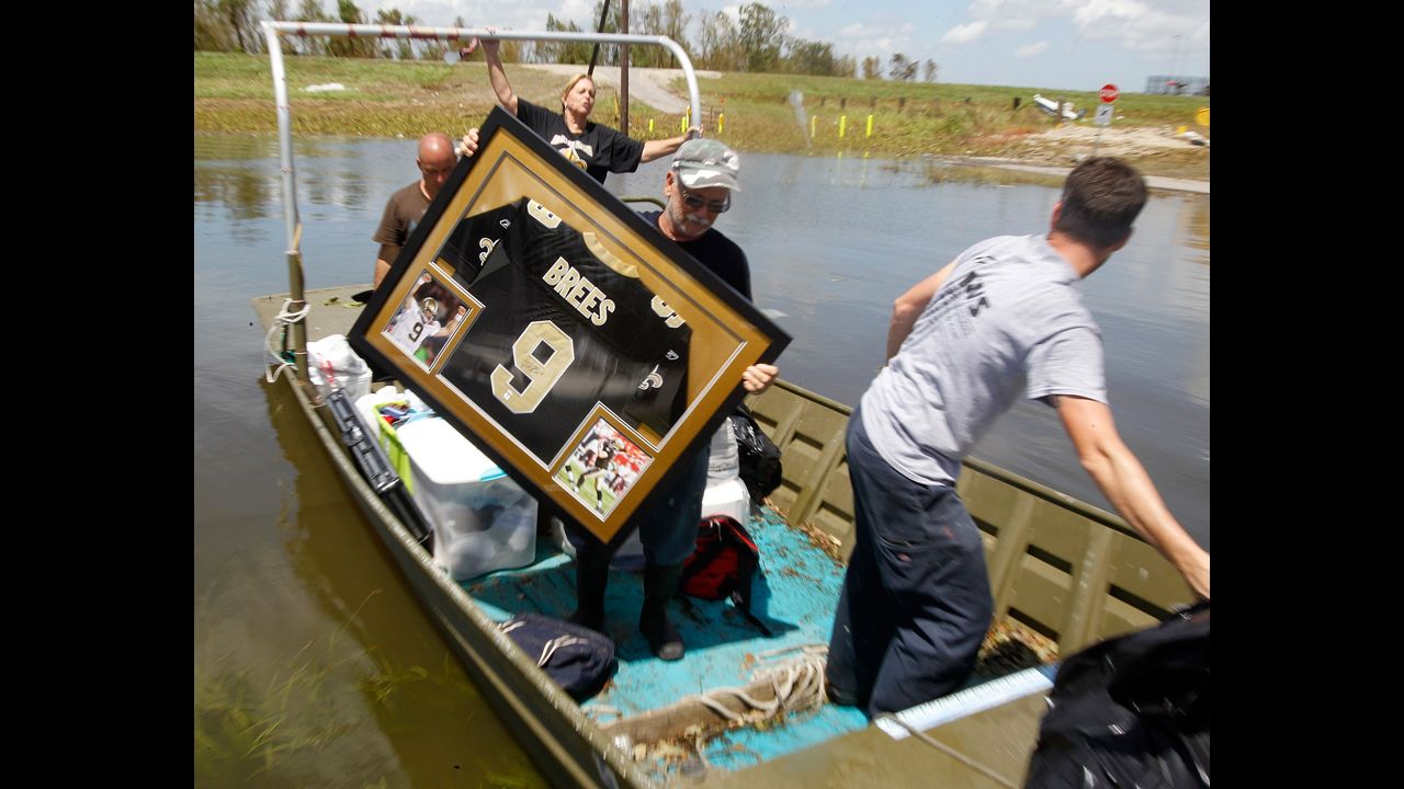 Russell Wilson, center, helps to move a water-damaged Drew Brees jersey from his daughter's home in Braithwaite.