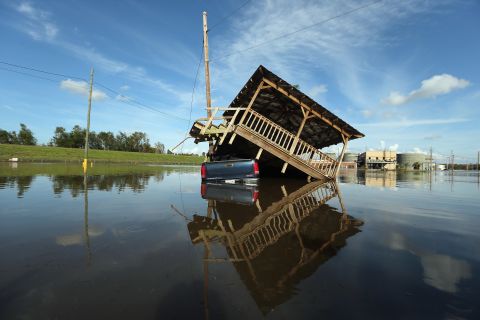 A damaged structure rests atop a partially submerged truck in Braithwaite, Louisiana.