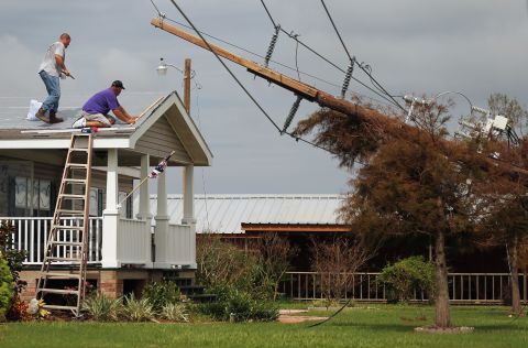 Workers repair the roof of a home as downed power lines caused by Hurricane Isaac lean onto a tree in lower Plaquemines Parish on Sunday, September 2.