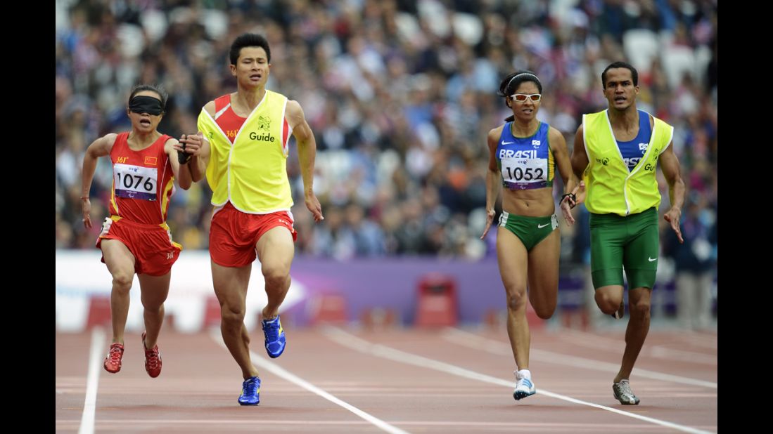 China's Jia Juntingxian, left, runs with her guide, Xu Dongloin, against Brazil's Jerusa Geber Santos and her guide, Luiz Henrique Barboza Da Silva, during the women's 200 meters T11 semifinal race.