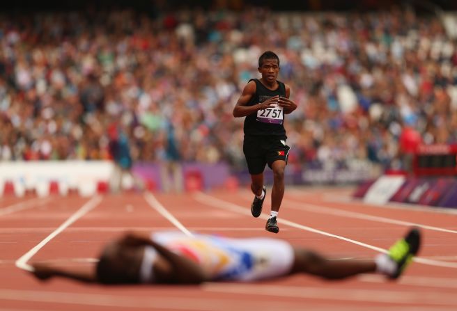 Filomeno Soares of East Timor competes in the men's 400-meter - T38 heats at Olympic Stadium. The winner, Venezuela's Omar Monterola, lies on the floor after crossing the finish line.